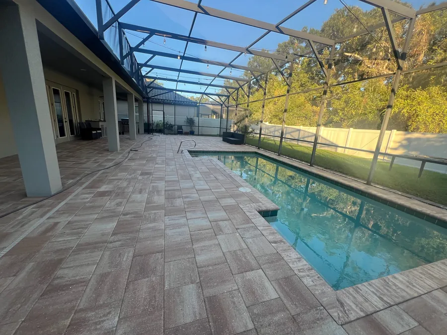Paver pool deck inside a screen enclosure in Oviedo, FL after cleaning and sealing